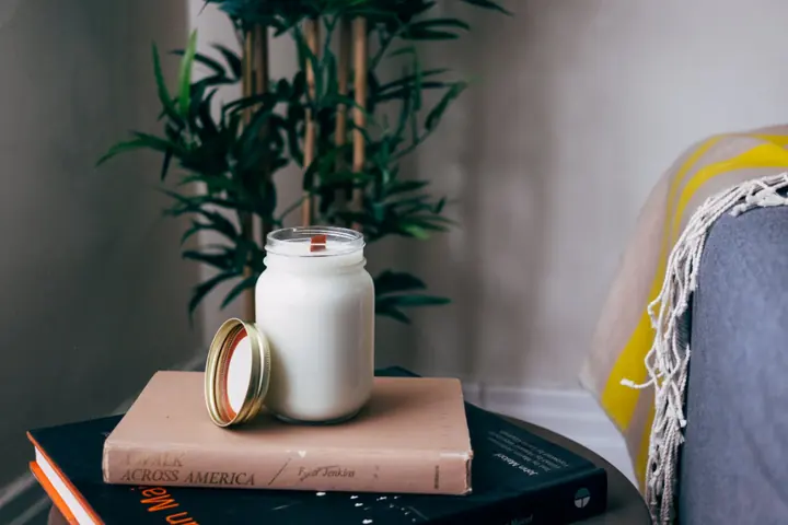 Handmade candle in a glass jar on a stack of books